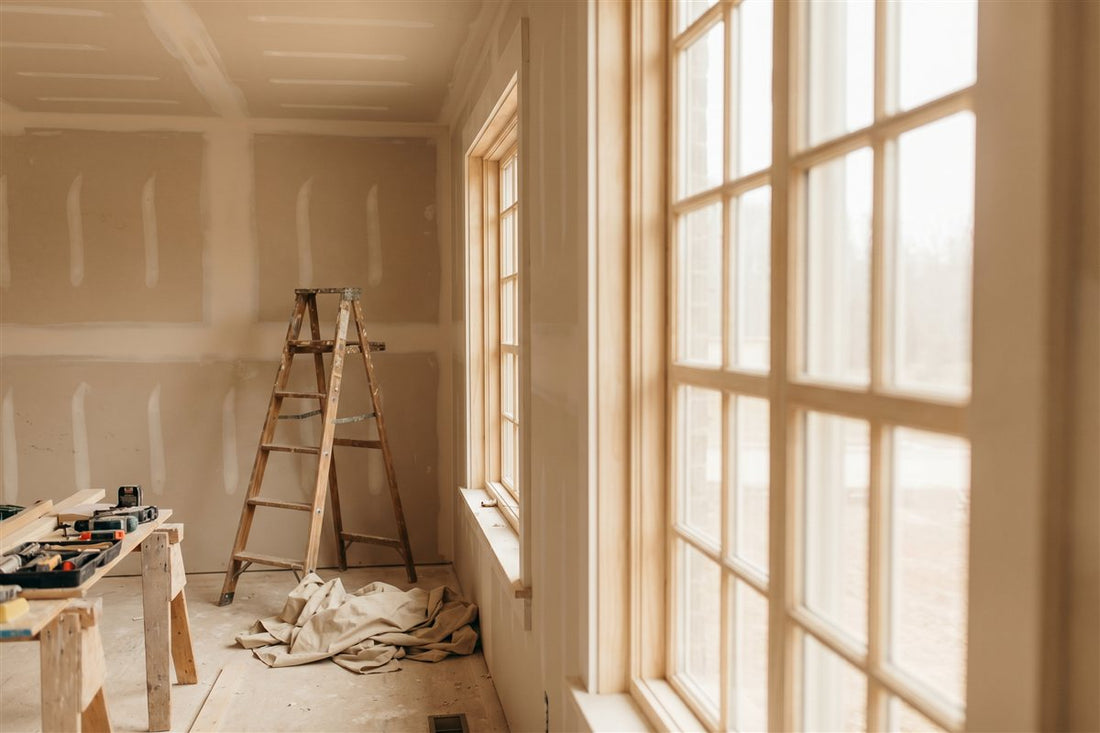 American home remodel in progress at the drywall stage with a step ladder and drop cloths