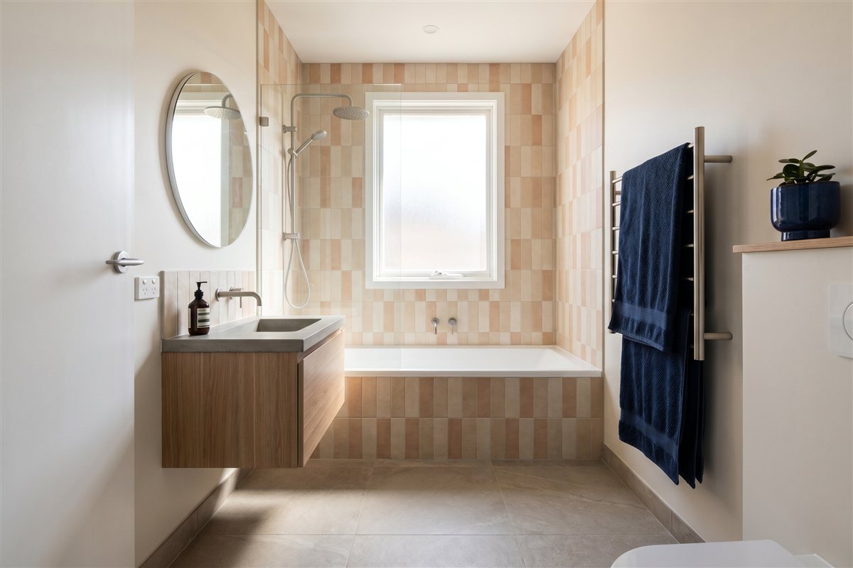 Renovated compact Australian bathroom with a shower-over-bath and floor-to-ceiling tiles