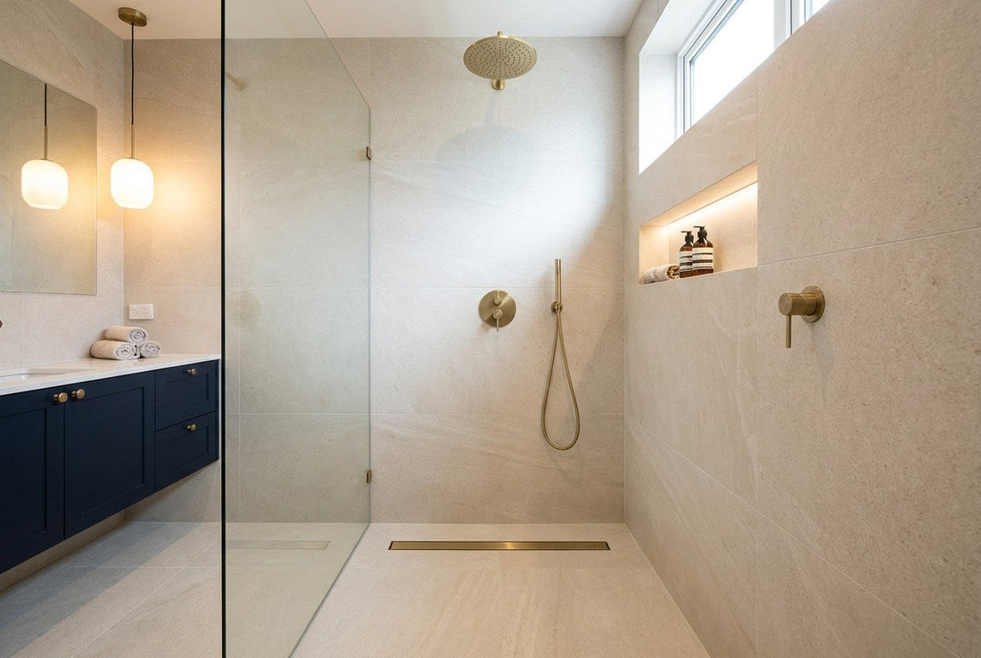 Renovated tiled walk-in shower with brass fittings and a navy vanity