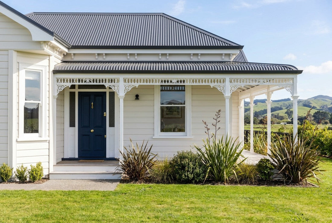Fully renovated New Zealand weatherboard villa with navy front door, brass hardware, veranda and native garden