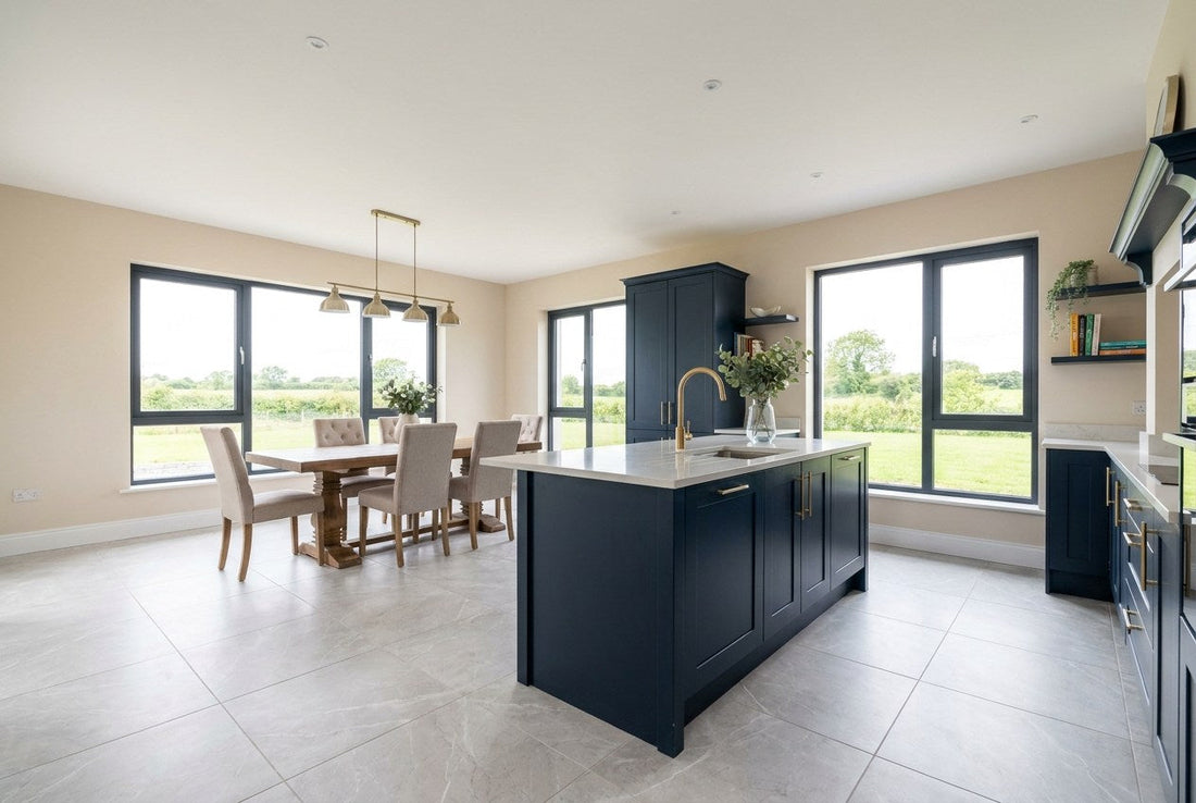 Finished open-plan Irish kitchen and dining room with a large-format pale grey porcelain tiled floor, navy cabinetry and brass tapware