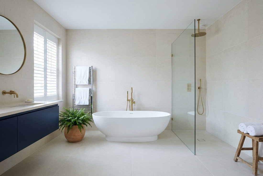 A completed family bathroom in a renovated UK home, with a freestanding bath, a brass floor-standing bath filler, a walk-in shower, a navy wall-hung vanity and plantation shutters