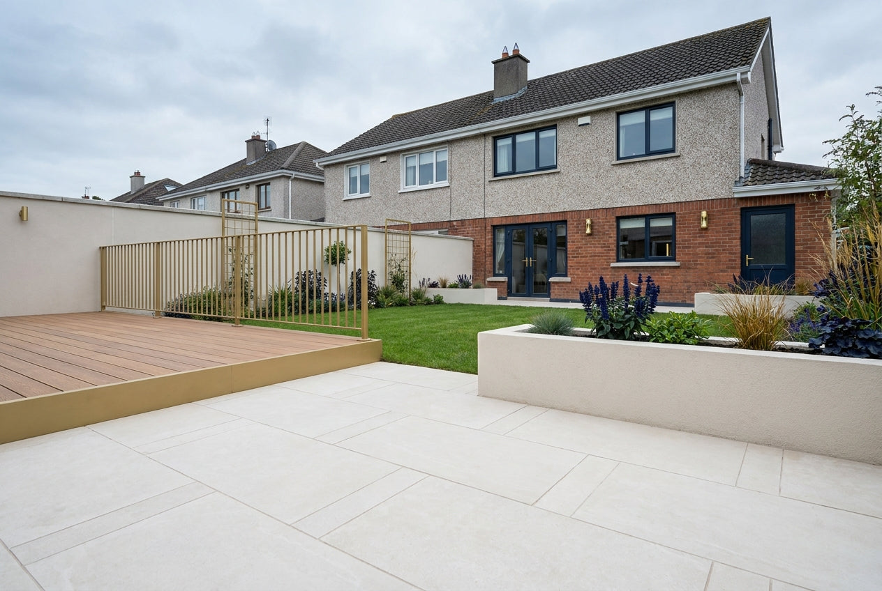 A renovated Irish back garden with pale stone patio paving, timber decking, lawn and planted borders behind a modern Irish house