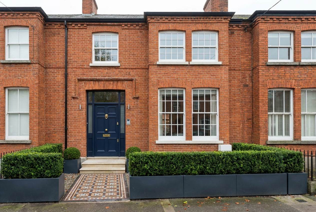 Fully renovated Irish redbrick terraced home with a navy front door, brass hardware and restored sash windows