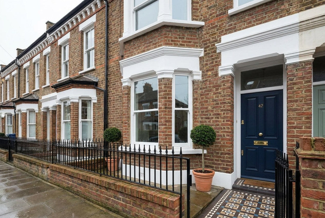A freshly renovated Victorian terraced house in the UK with a navy front door, brass hardware and a tiled path, the finished result of hiring a verified builder