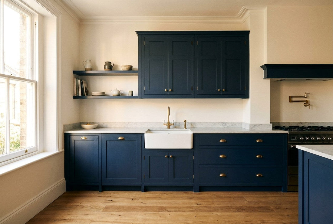 Renovated kitchen with navy units, brass handles and a pale stone worktop