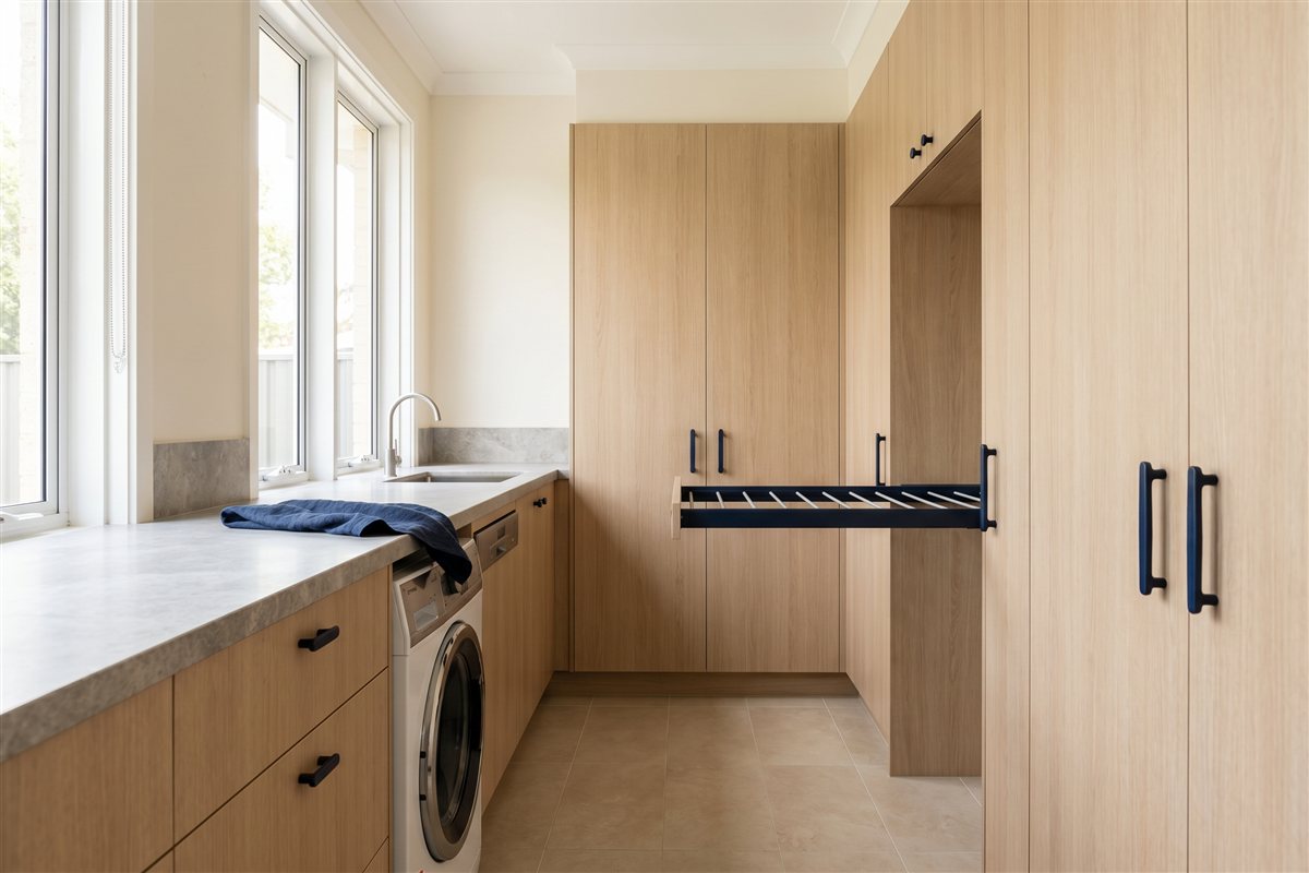 Renovated Australian laundry with full-height cabinetry, a stone benchtop and an integrated washing machine