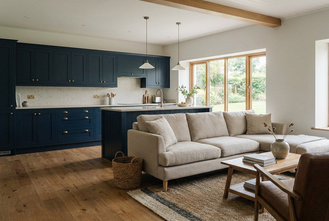 Finished open-plan Irish kitchen and living space with navy shaker cabinetry, brass handles, stone worktop and oak flooring, opening to a garden