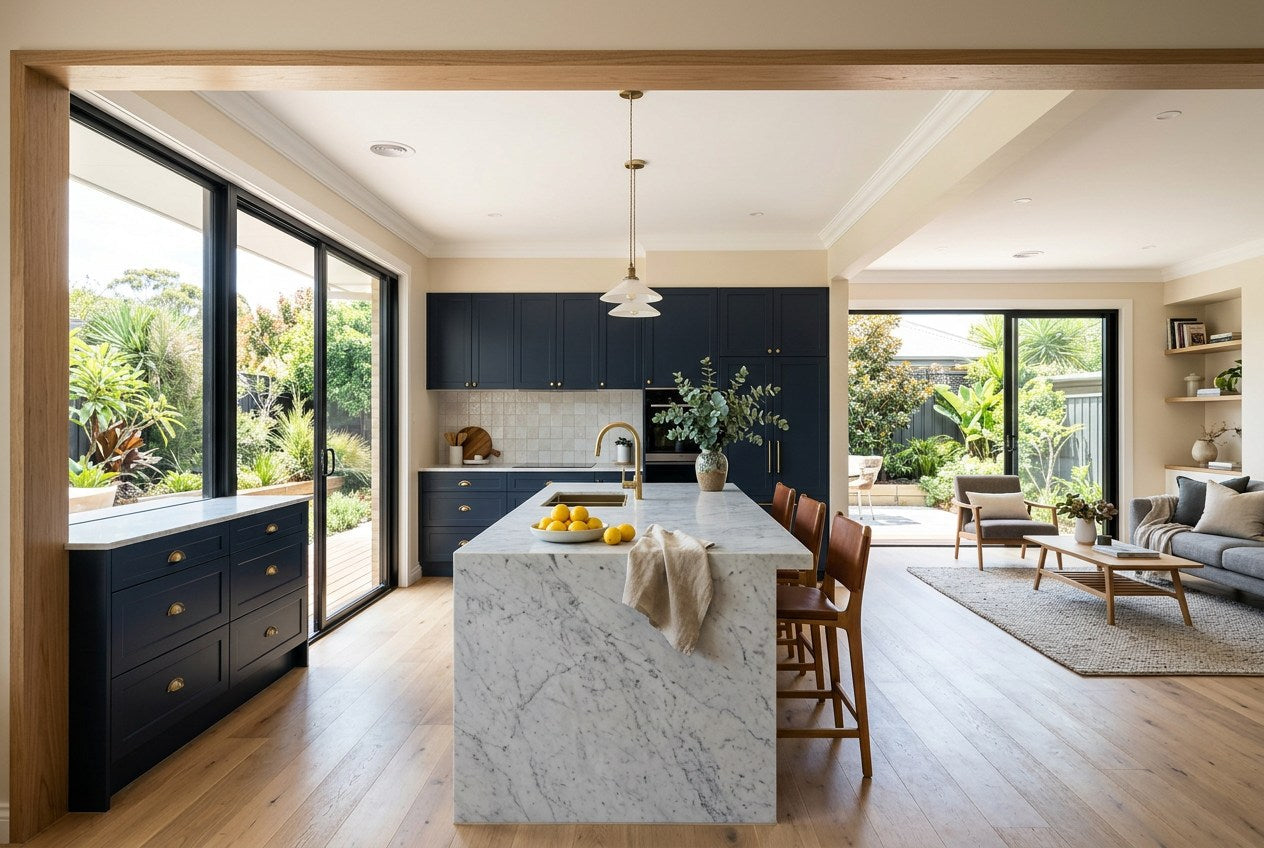 Completed open-plan Australian kitchen and living space with navy cabinetry, brass tapware and a stone benchtop