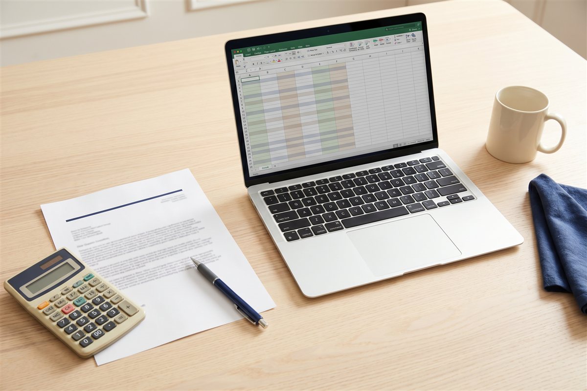 Renovation budget review with a laptop spreadsheet, printed quote, calculator and pen