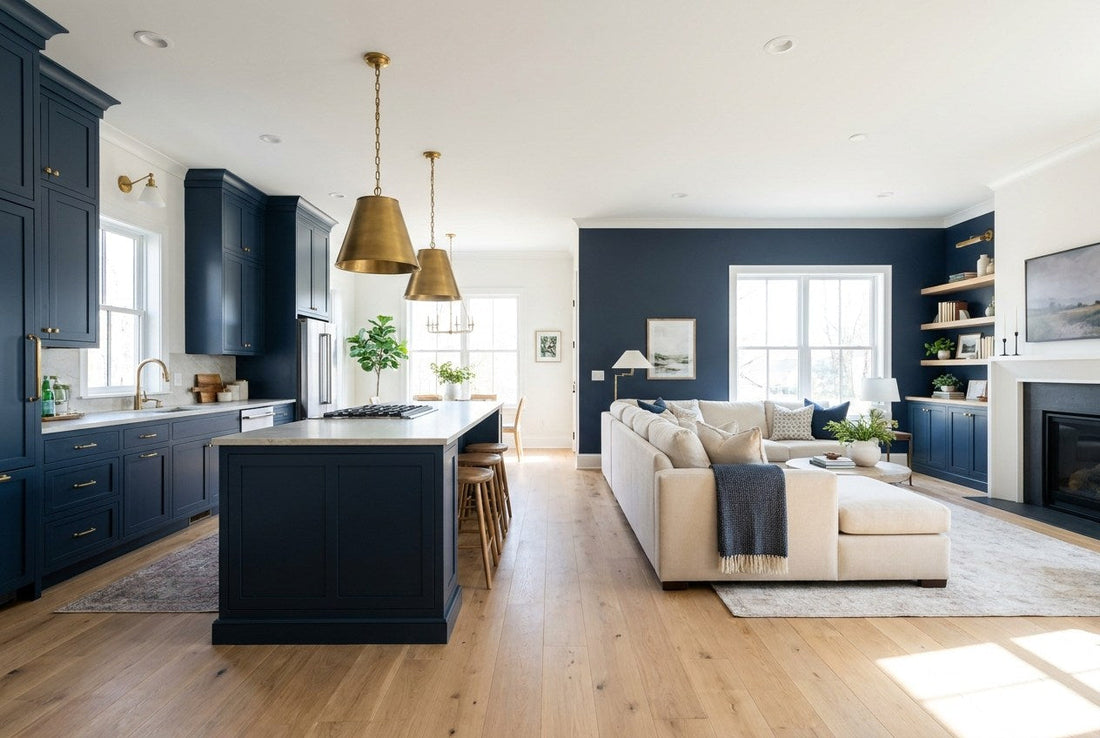 Fully renovated open-plan American kitchen and living room with navy cabinetry, brass pendant lights, pale stone countertop and light oak floors