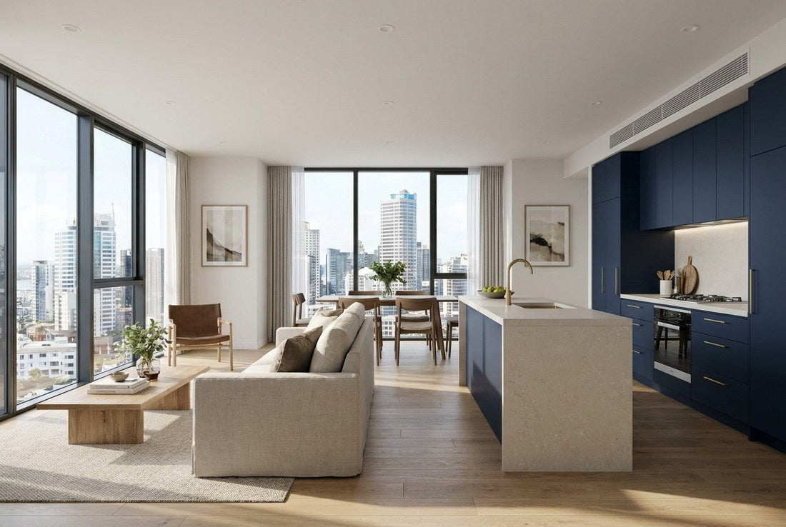 Finished open-plan living and kitchen in a renovated New Zealand apartment with a high-rise city view, navy cabinetry, stone island and brass tapware.