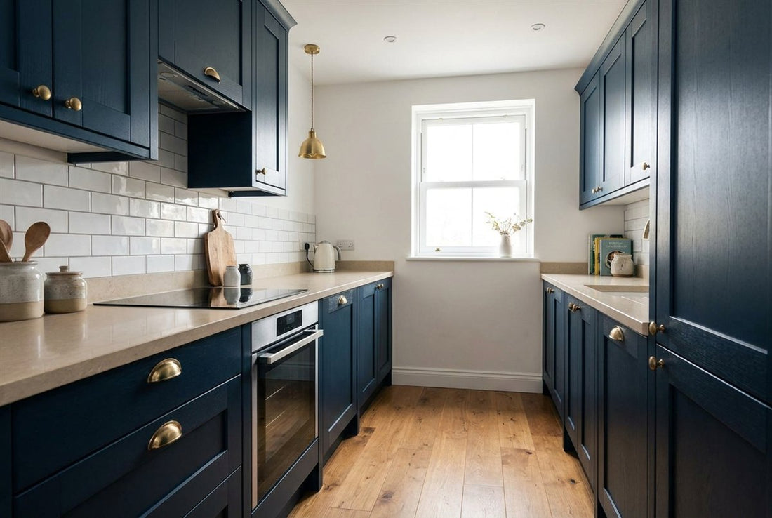 Finished compact navy Shaker galley kitchen with brass cup handles, a pale quartz worktop, white metro-tile splashback and oak flooring