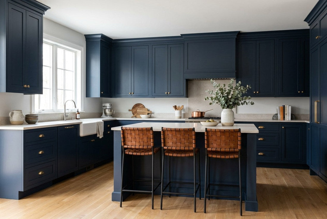 Finished navy shaker kitchen cabinets with brushed brass cup pulls and a pale stone countertop and island