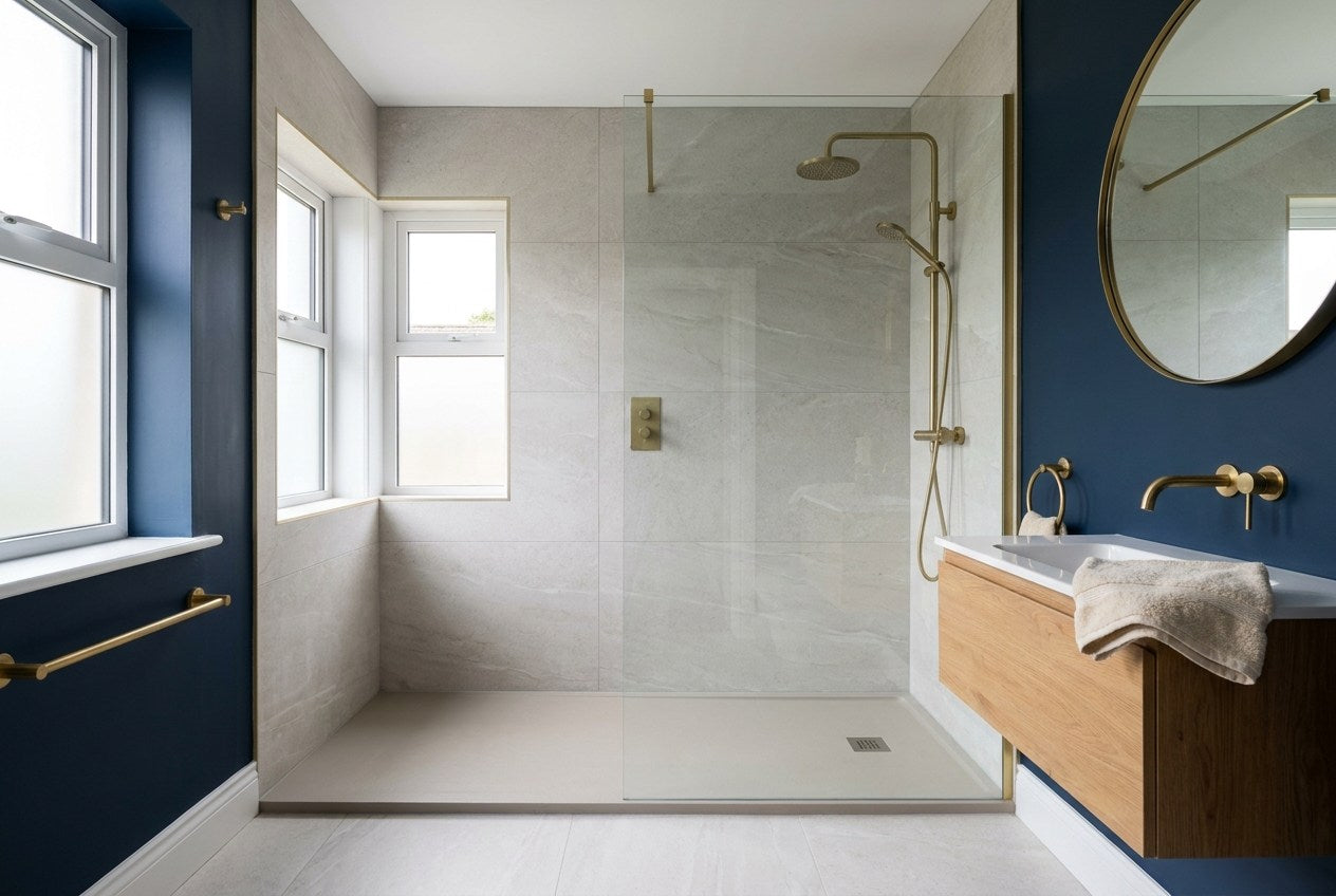Finished walk-in shower in an Irish bathroom with frameless glass panel, low-profile tray, brass shower valve and pale stone tiling