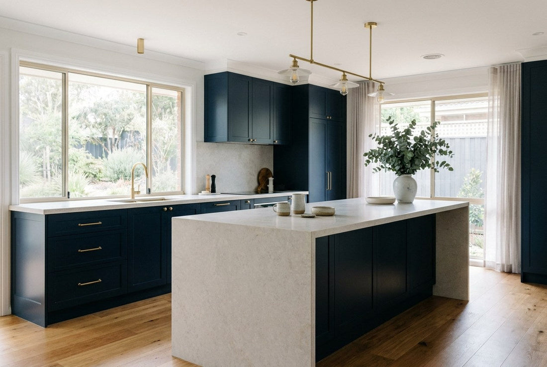 A calm, completed Australian kitchen renovation in navy and brass with pale stone benchtops